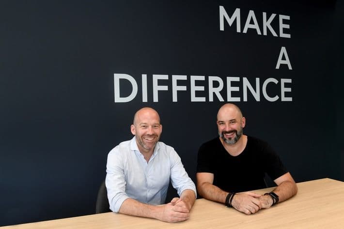 Credaris und Milenia besiegeln Zusammenarbeit – Foto zweier Geschäftsführer vor ‚Make a Difference‘-Wand