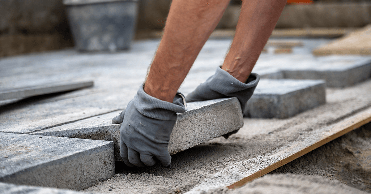 Hände verlegen Pflastersteine – Symbol für solides Fundament, Verlässlichkeit und Werteorientierung bei Credaris