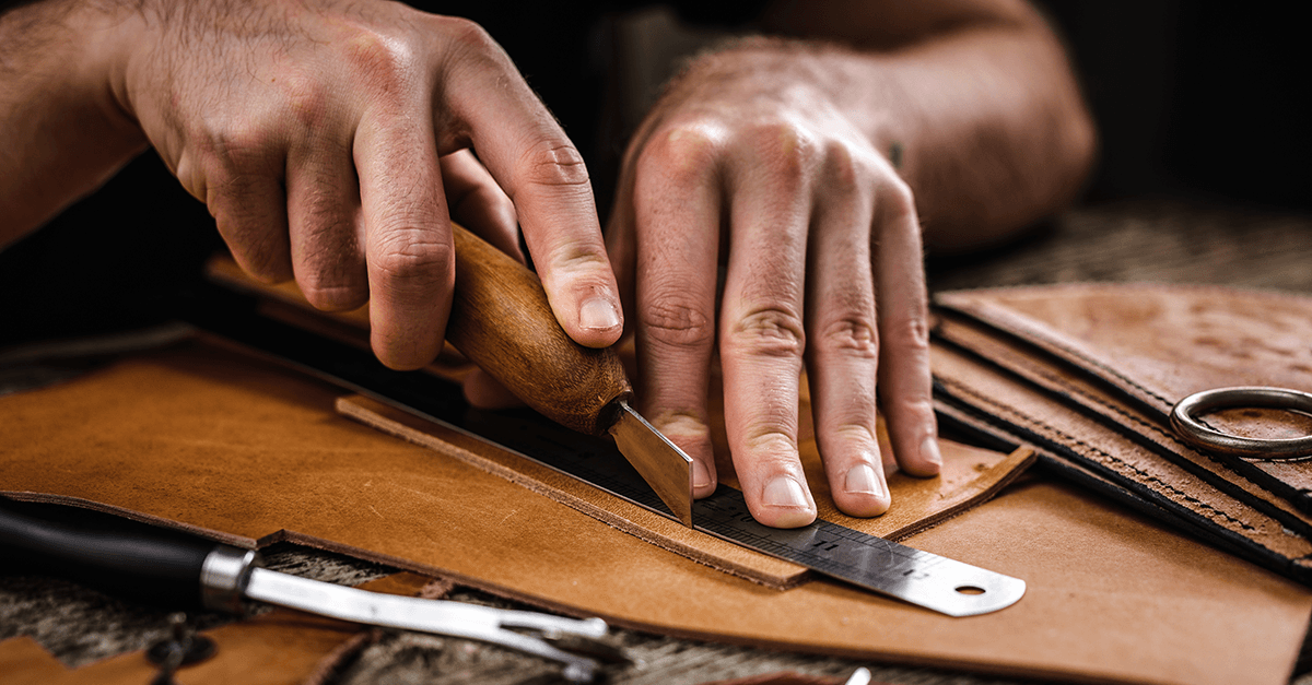 Handwerker bearbeitet Stück Leder mit Präzision - Symbol für genaue Arbeit